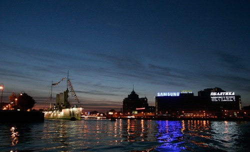 The Cruiser Aurora next to billboards on the Neva.